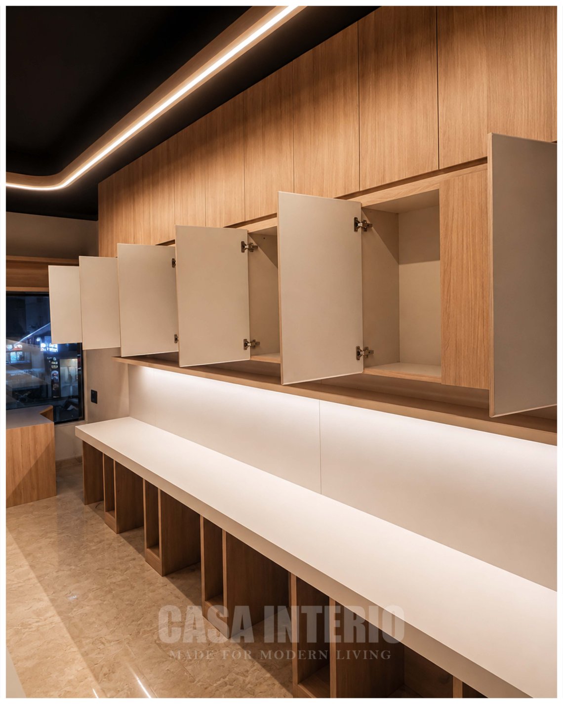 Overhead storage cabinets open above backlit workstation counters